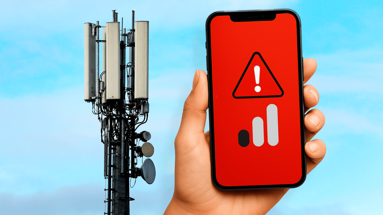 a hand holds a phone showing no signal with a 3G mast in the background