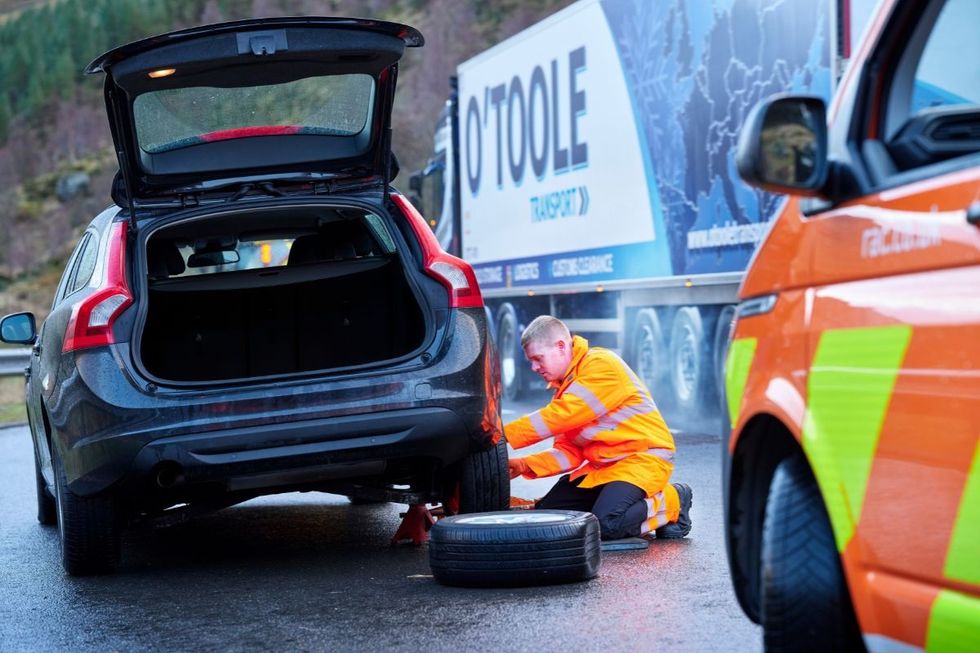 A mechanic fixing a car wheel on the side of the road