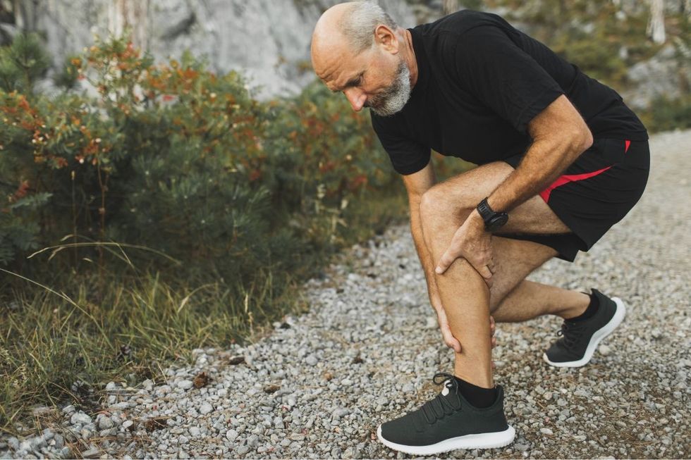 MAN HOLDING CALF MUSCLE