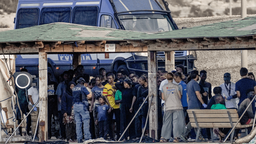 Migrant survivors stand on the dock