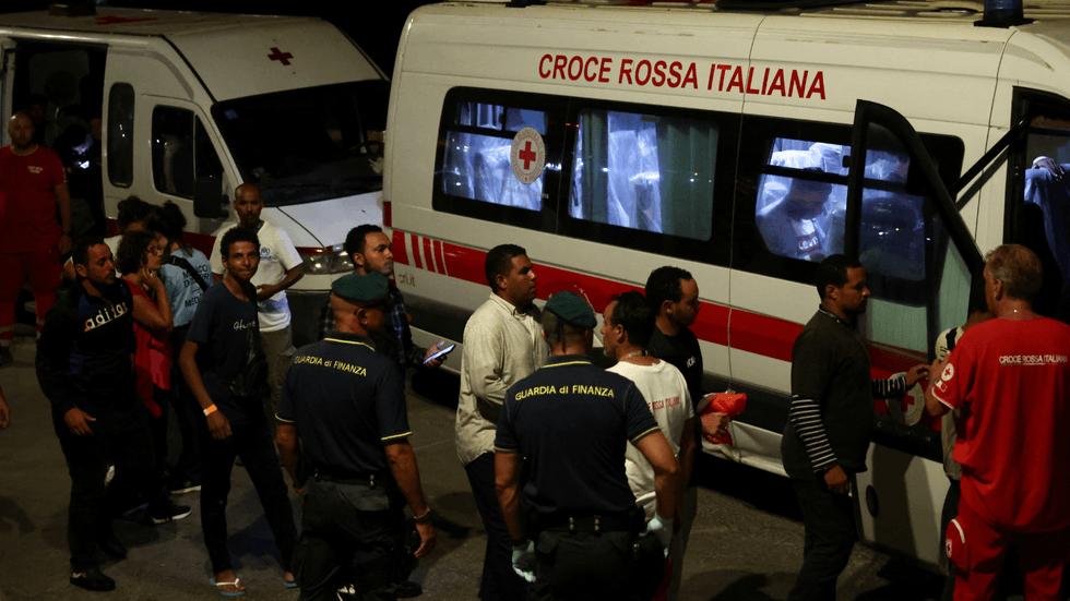 Migrants rescued at sea walk to board a Red Cross vehicle