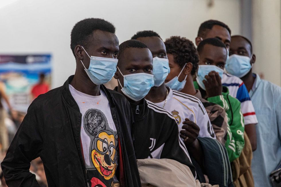 Newly-arrived migrants line up inside a municipal hall in the town of Agyia, on the island of Crete, Greece