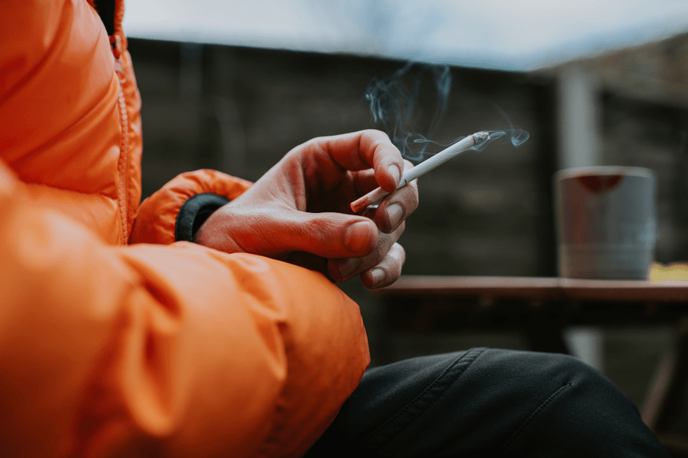 Person in an orange coat holding a cigarette