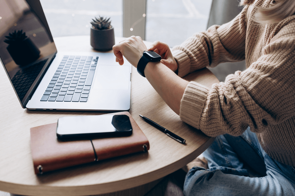 Someone checking their watch by a laptop